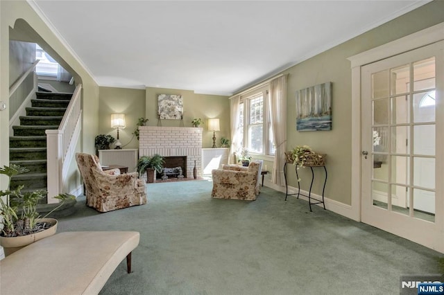 living area featuring a brick fireplace, crown molding, baseboards, stairs, and carpet flooring