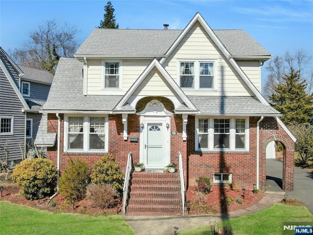 view of front of home with brick siding and a shingled roof