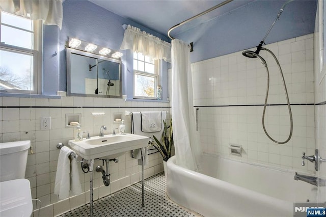 bathroom with toilet, a sink, tile walls, shower / tub combo, and tile patterned flooring