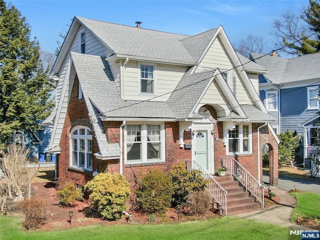 view of front of house featuring brick siding and roof with shingles