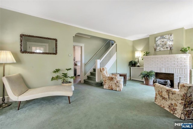 sitting room featuring baseboards, carpet floors, a fireplace, ornamental molding, and stairs