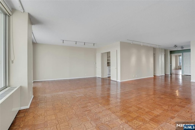 spare room with baseboards, a textured ceiling, and rail lighting