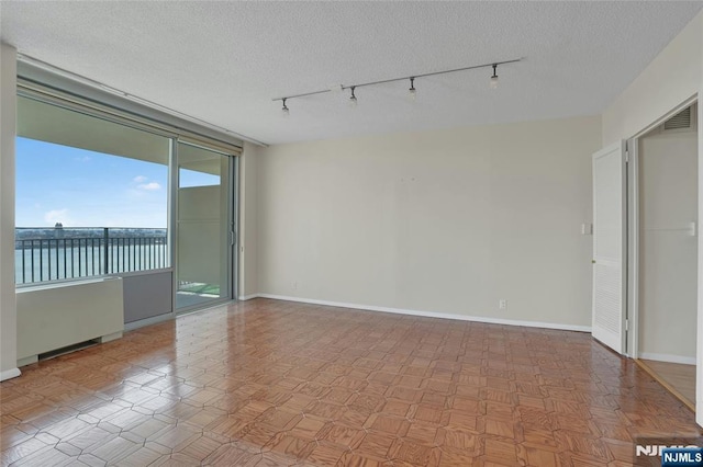 spare room with visible vents, baseboards, a textured ceiling, and rail lighting