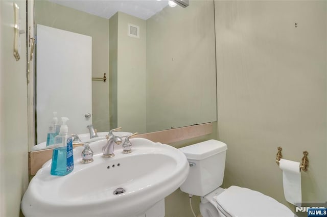 bathroom featuring toilet, visible vents, and a sink