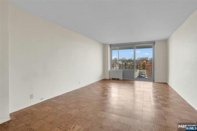 unfurnished room with radiator and a wall of windows