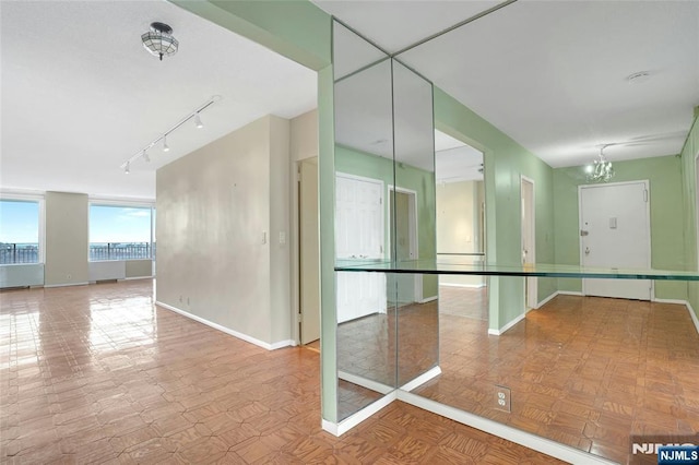 spare room with baseboards, a chandelier, and rail lighting