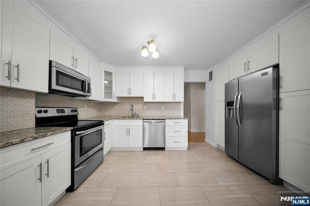 kitchen with stone countertops, a sink, white cabinets, appliances with stainless steel finishes, and backsplash