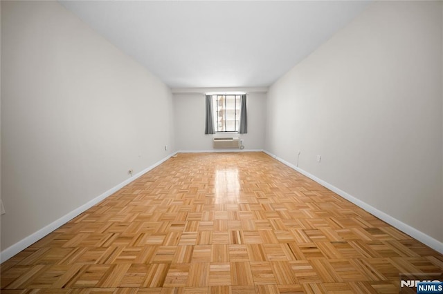 empty room with an AC wall unit and baseboards