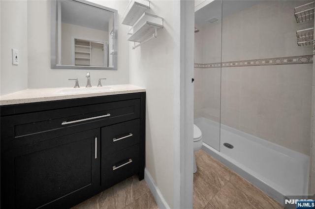 bathroom with baseboards, vanity, toilet, and a shower stall