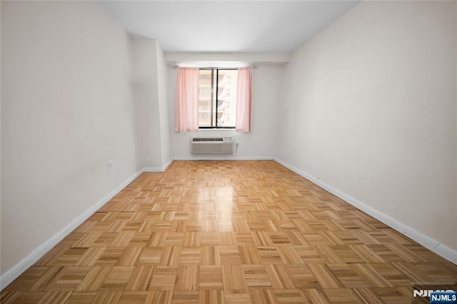 empty room featuring a wall mounted AC and baseboards