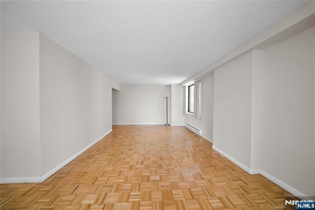 spare room featuring a baseboard heating unit, baseboards, and a textured ceiling