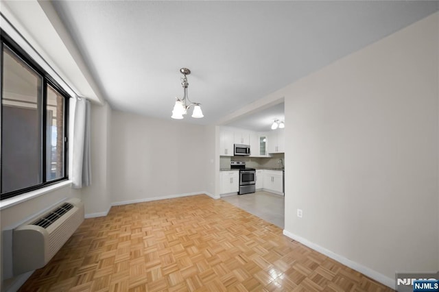 unfurnished dining area featuring baseboards, an inviting chandelier, and a wall unit AC