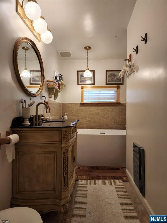 full bath featuring a washtub, visible vents, and vanity