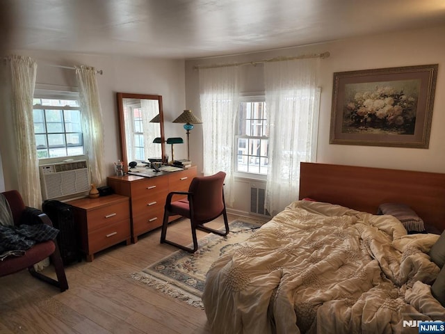 bedroom with cooling unit and light wood-style flooring