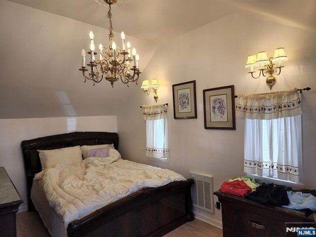 bedroom with lofted ceiling, visible vents, and wood finished floors