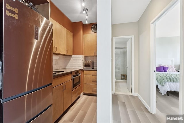 kitchen with baseboards, a toaster, appliances with stainless steel finishes, light wood-type flooring, and backsplash