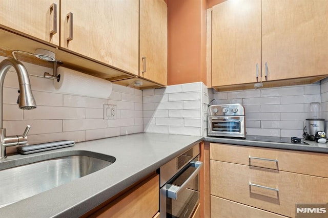 kitchen featuring tasteful backsplash, a toaster, light brown cabinets, and a sink