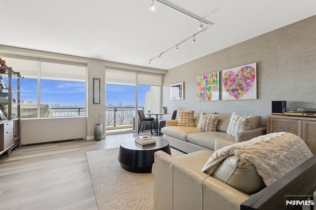 living area featuring rail lighting, light wood-style floors, an accent wall, and wallpapered walls