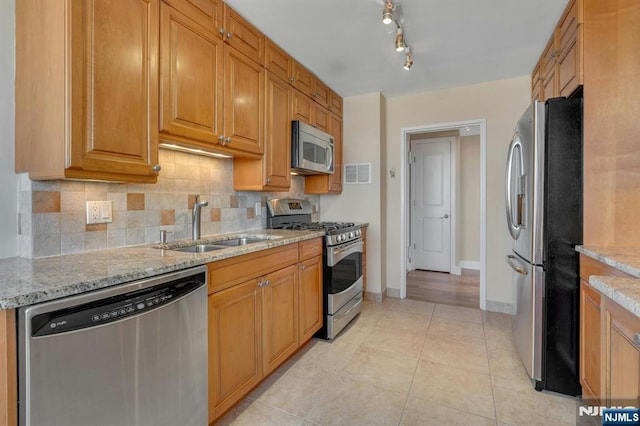 kitchen featuring visible vents, a sink, backsplash, stainless steel appliances, and light stone countertops