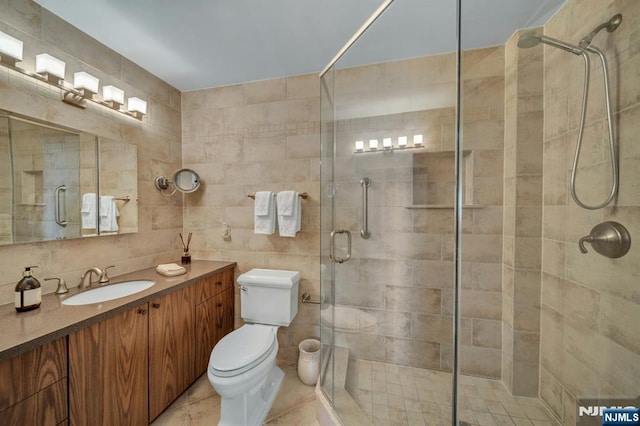 full bath with a shower stall, vanity, toilet, and tile walls