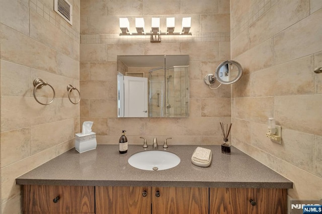 bathroom featuring vanity, a shower stall, and visible vents