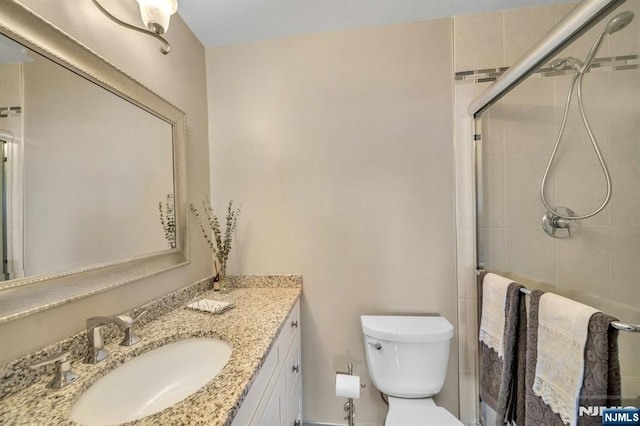 bathroom with toilet, a stall shower, and vanity