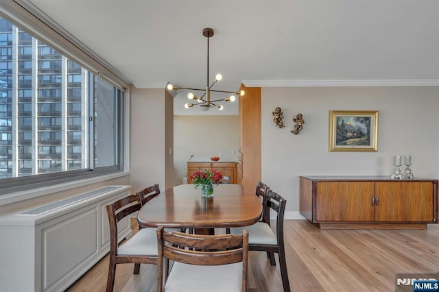 dining area featuring baseboards, light wood-type flooring, crown molding, and an inviting chandelier