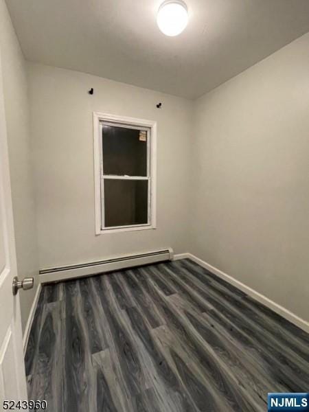 empty room with baseboards, a baseboard heating unit, and wood finished floors