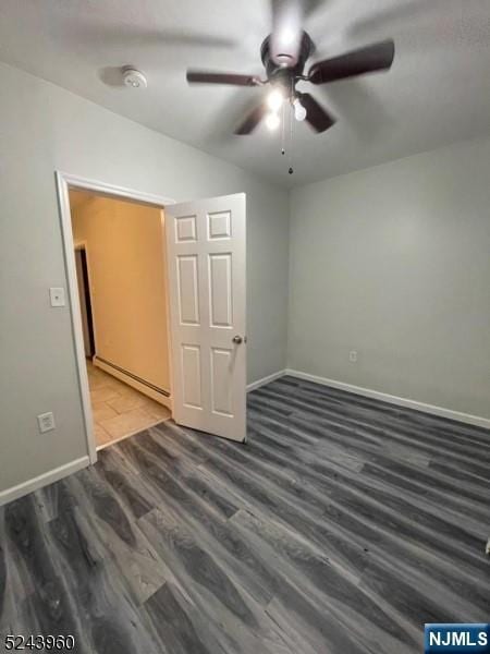 spare room featuring lofted ceiling, baseboard heating, wood finished floors, and baseboards