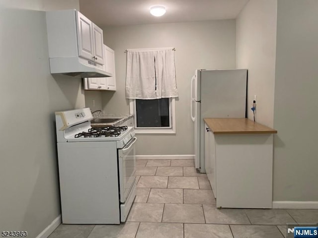 kitchen featuring white appliances, white cabinetry, under cabinet range hood, and baseboards