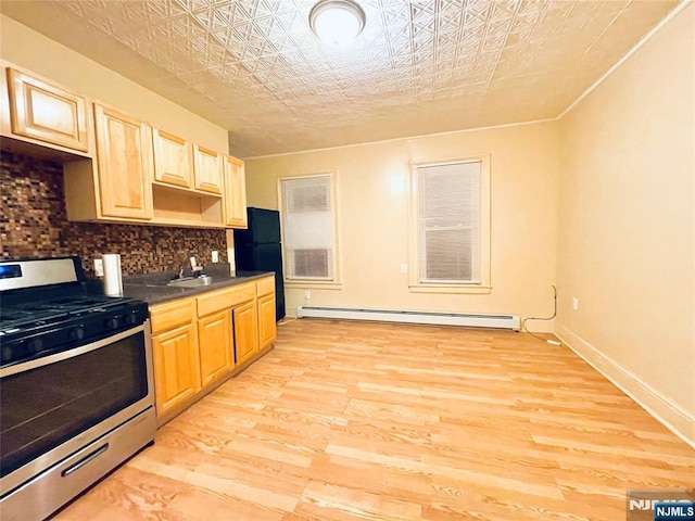 kitchen featuring a baseboard radiator, stainless steel range with gas stovetop, freestanding refrigerator, decorative backsplash, and an ornate ceiling