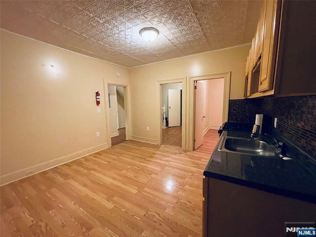 kitchen featuring tasteful backsplash, light wood-type flooring, a sink, and an ornate ceiling