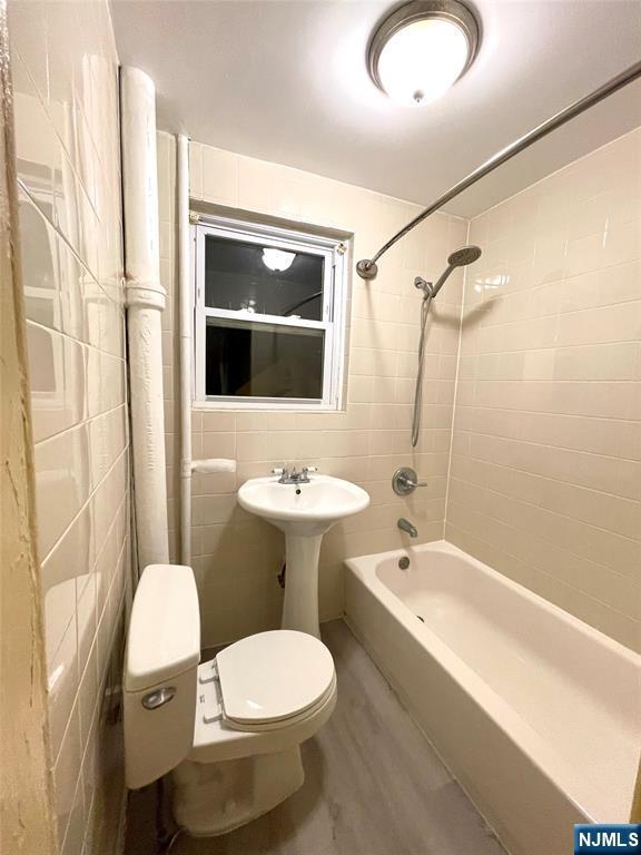 full bathroom featuring shower / tub combination, tile walls, toilet, and wood finished floors