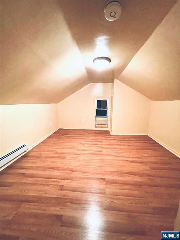 additional living space with lofted ceiling, a baseboard heating unit, baseboards, and wood finished floors