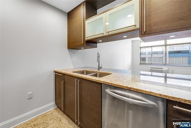 kitchen featuring stainless steel dishwasher, a sink, light stone counters, and baseboards