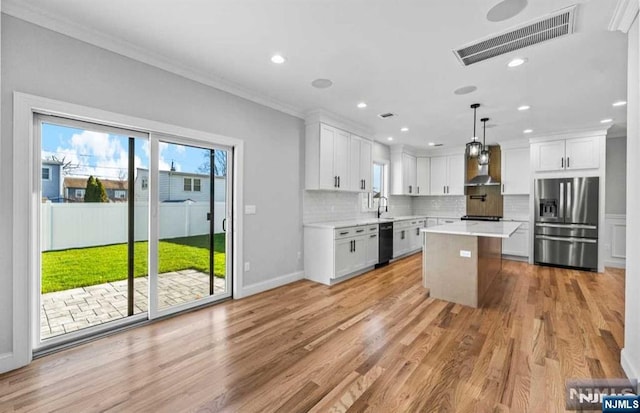 kitchen with visible vents, black dishwasher, light countertops, wall chimney range hood, and stainless steel fridge with ice dispenser