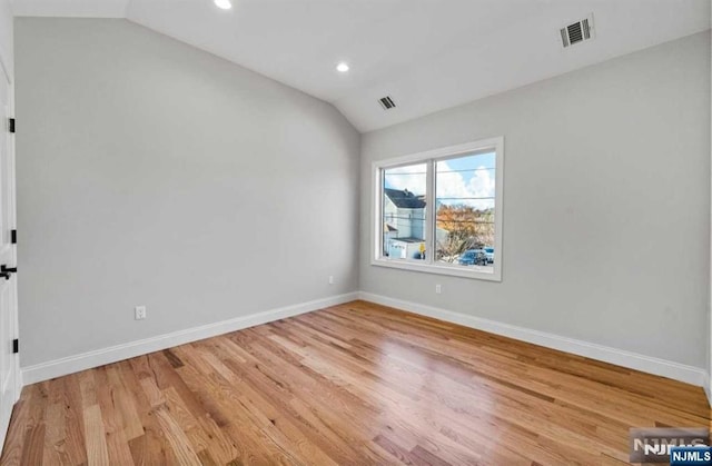 spare room featuring lofted ceiling, visible vents, and baseboards