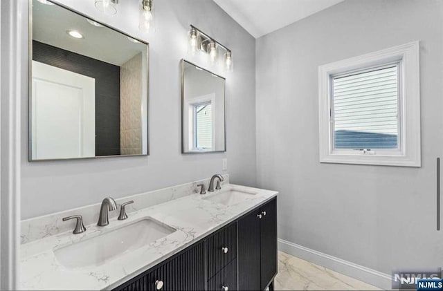 bathroom with marble finish floor, a sink, baseboards, and double vanity