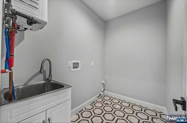 clothes washing area featuring cabinet space, baseboards, light floors, washer hookup, and a sink