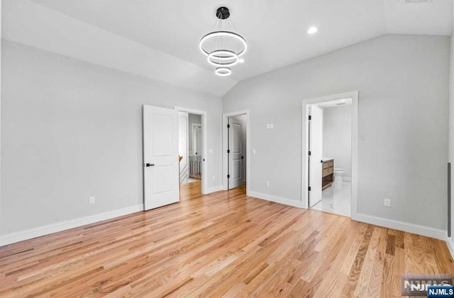 unfurnished bedroom featuring lofted ceiling, ensuite bathroom, light wood-style flooring, and baseboards