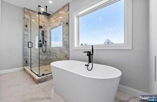 bathroom with marble finish floor, baseboards, a freestanding bath, and a marble finish shower