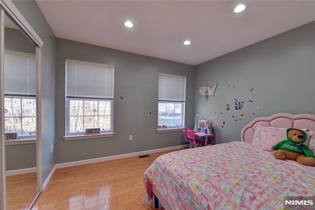 bedroom with light wood finished floors, visible vents, multiple windows, and baseboards