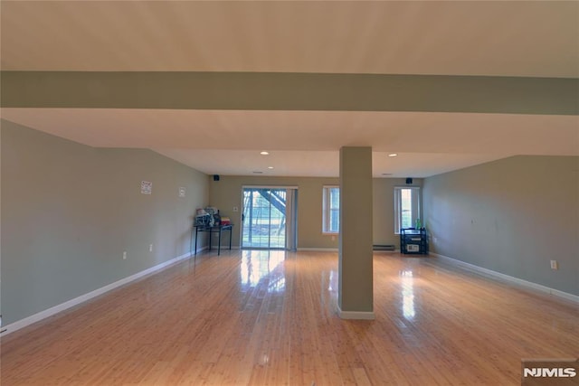 unfurnished room with baseboards, baseboard heating, a healthy amount of sunlight, and light wood finished floors