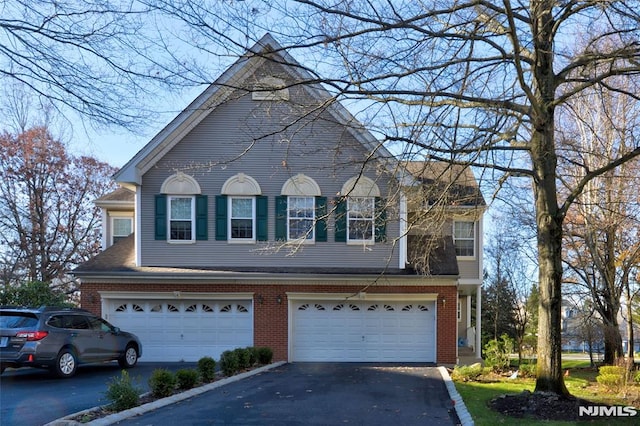 view of front of property with aphalt driveway, an attached garage, and brick siding