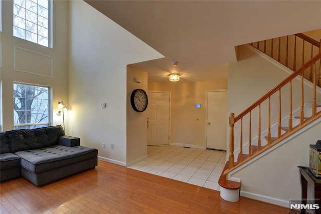 entrance foyer featuring stairs, wood finished floors, baseboards, and a towering ceiling