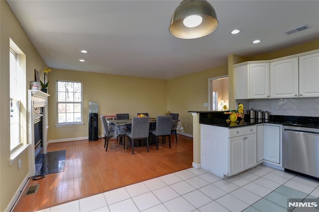 kitchen with visible vents, white cabinets, dishwasher, dark countertops, and tasteful backsplash