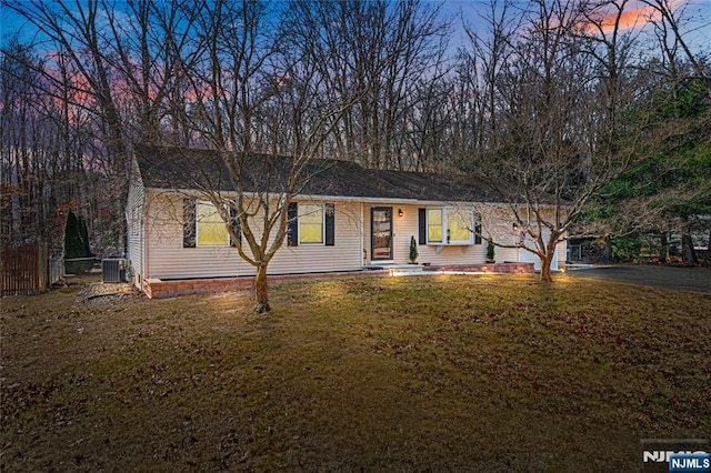 single story home with driveway, fence, cooling unit, and a lawn