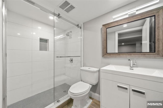 full bathroom with visible vents, a shower stall, baseboards, toilet, and vanity