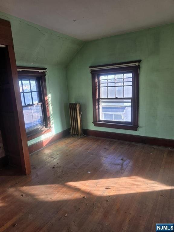 bonus room featuring lofted ceiling, wood-type flooring, baseboards, and radiator