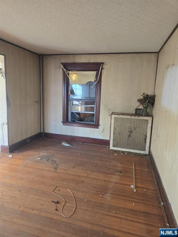 spare room with a textured ceiling, baseboards, and hardwood / wood-style flooring